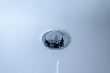 Silver drain in a white sink in the bathroom