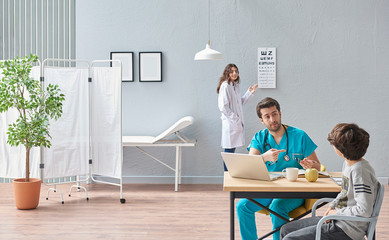 Obraz premium Ophthalmologist suggest wearing glasses for young boy in the health center. Modern office room for doctors.