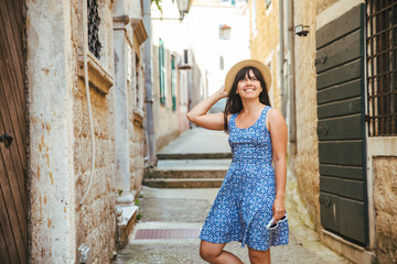 young pretty woman in blue dress walking by little streets of Herceg Novi