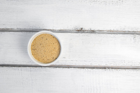 Amaranth seeds in white ceramic bowl isolated on grey backround from above.