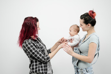 Two young women with a baby on a white background. Same-sex marriage and adoption, homosexual lesbian couple.