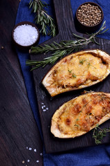 Stuffed eggplant halves roasted with cheese on a black cutting board