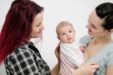 Two young women with a baby on a white background. Same-sex marriage and adoption, homosexual lesbian couple.