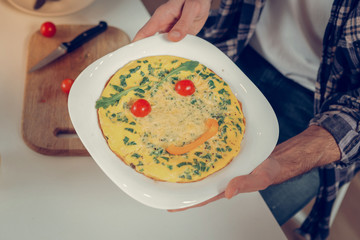 Bearded tall man in a checkered shirt demonstrating an omelet