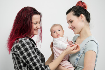 Two young women with a baby on a white background. Same-sex marriage and adoption, homosexual lesbian couple.