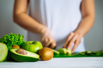 green fruits on front. woman cut fruits on background. healthy food concept