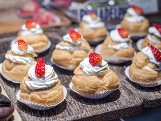 Fresh cream puffs filled with whipped cream and strawberry on top