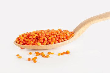 red lentils in a wooden spoon isolated on white background