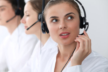 Call center operators at work. Focus at beautiful business woman in headset