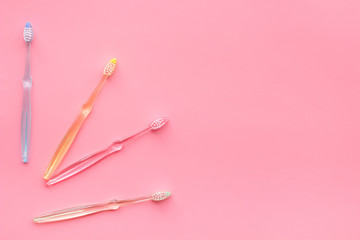 Oral hygiene. Plastic toothbrushes on pink background top view copy space