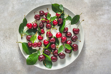Fresh cherries on plate. Red sweet cherry fruit, flat lay, top view.