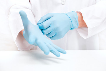 man-doctor wears medical gloves on while standing against a white background