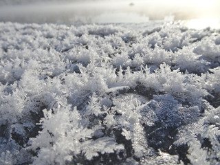 Crystals of snowflakes on the ice against a frozen river