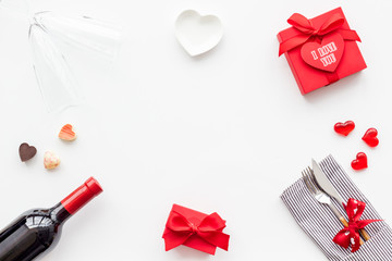 Romantic dinner on Valentine's day. Decorated dishes, tableware, wine and gift box on white background top view copy space