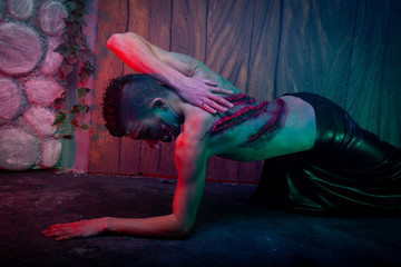 scary vampire male with huge teeth and bloody body as halloween body art standing in the night...