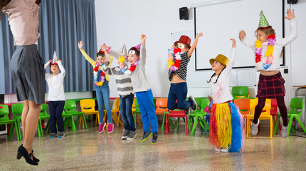 Obraz premium Pupils and teacher in festive hats jumping