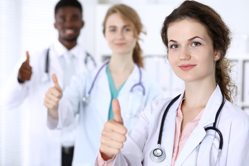 Fototapeta premium Happy doctor woman showing Ok sign with medical staff at the hospital. Multi ethnic people group