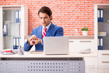 Young handsome employee working in the office 