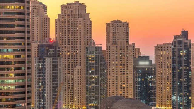 Dubai marina and JBR twers panorama day to night transition timelapse lights turn on. The night illumination of skyscrapers, UAE. Aerial view from JLT