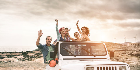 Happy tourists friends doing excursion on desert in convertible 4x4 car