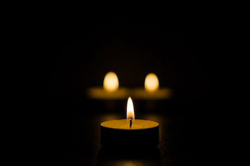 Three burning candles isolated on black background.