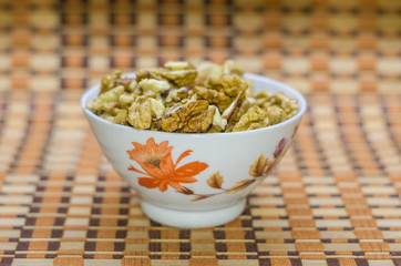 Walnuts in a white bowl on a brown beautiful background.