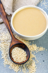 Bowl of tahini and spoon with white sesame seeds.