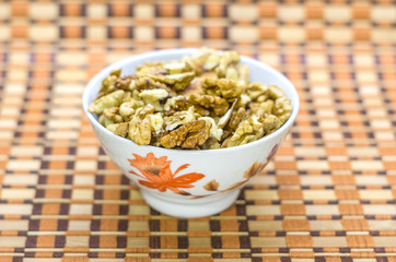 Walnuts in a white bowl on a brown beautiful background.