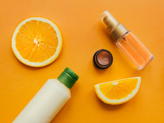 Skincare products Flat lay photo Lotion, cosmetic oil, facial cream are lying on yellow background with slices of orange