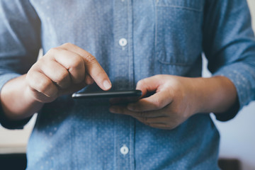 Casual man using a smart phone texting messages.