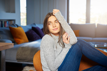 Young woman relaxing in armchair at home on a lazy day