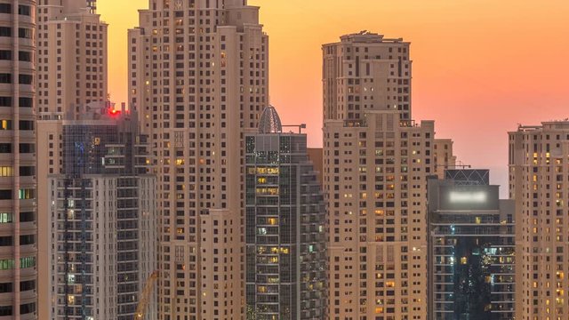 Dubai marina and JBR twers panorama day to night transition timelapse lights turn on. The night illumination of skyscrapers, UAE. Aerial view from JLT