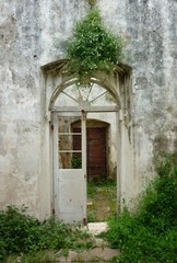 Fototapeta na wymiar Interior of an abandoned old haunted house without roof with green plants view of wooden broken doors in Corfu island
