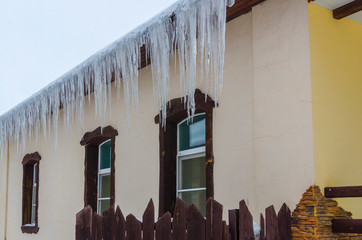 Ледяные образования (сосульки) на краю крыши дома.