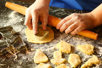 Closeup of woman's hands working with dough and making biscuits