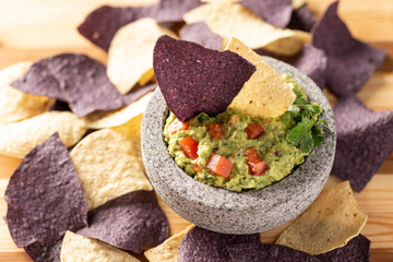 Granite Mulcajete filled with fresh guacamole surrounded by blue and yellow tortilla chips