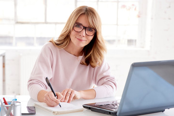 Middle aged businesswoman sitting at office desk and working on business plan