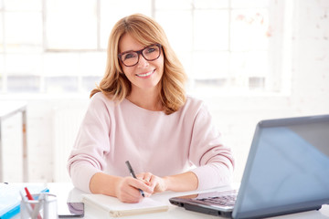 Middle aged businesswoman sitting at office desk and working on business plan