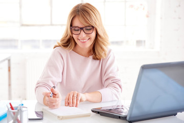 Middle aged businesswoman sitting at office desk and working on business plan