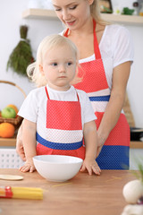 Fototapeta premium Happy mother and little daughter cooking in kitchen. Spending time all together, family fun concept