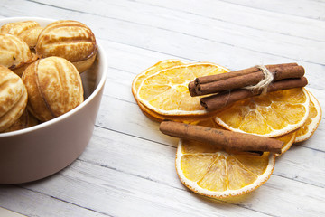 Bowl with cookies - nuts and orange slices with cinnamon on a light wooden background
