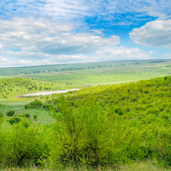 Fototapeta na wymiar Green field and blue sky. Picturesque hills formed by an old river terrace. Moldova. Agricultural landscape.