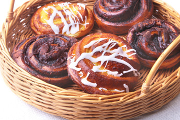 Freshly baked homemade sweet bun or sweet rolls with cinnamon in a wicker basket.