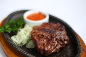 Стейк з чашкою соусу, петрушкою та цибулею. З невеликою глибиною різкості