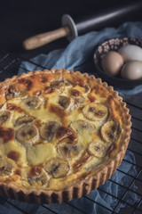 Banana custard tart with rolling pin and ingredients. Vertical