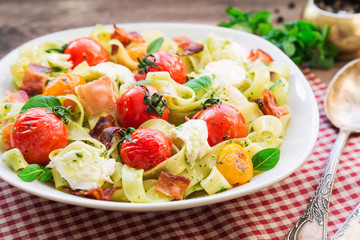 Fettuccine pasta with baked tomatoes, bacon and mozzarella cheese