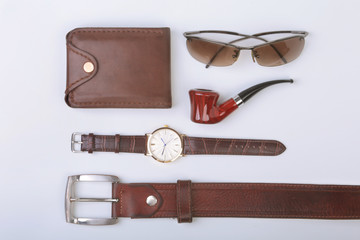 Men's accessories for business and rekreation. Leather belt, wallet, watch and smoking pipe on white background.. Top view composition.