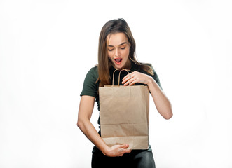 Portrait of surprised attractive long-haired woman looking into paper bag over the white...