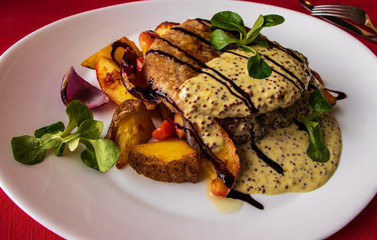 Pork tenderloin with slices of baked potatoes, apples, tomatoes and onions, drizzled with creamy sauce with Dijon mustard.
