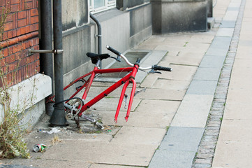 Bicycle remains tethered to a drainpipe on a deserted street